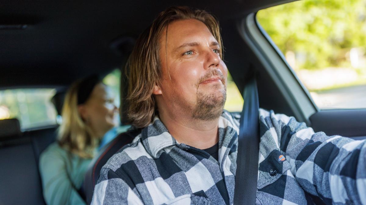 En man kör bil, en kvinna sitter i baksätet.