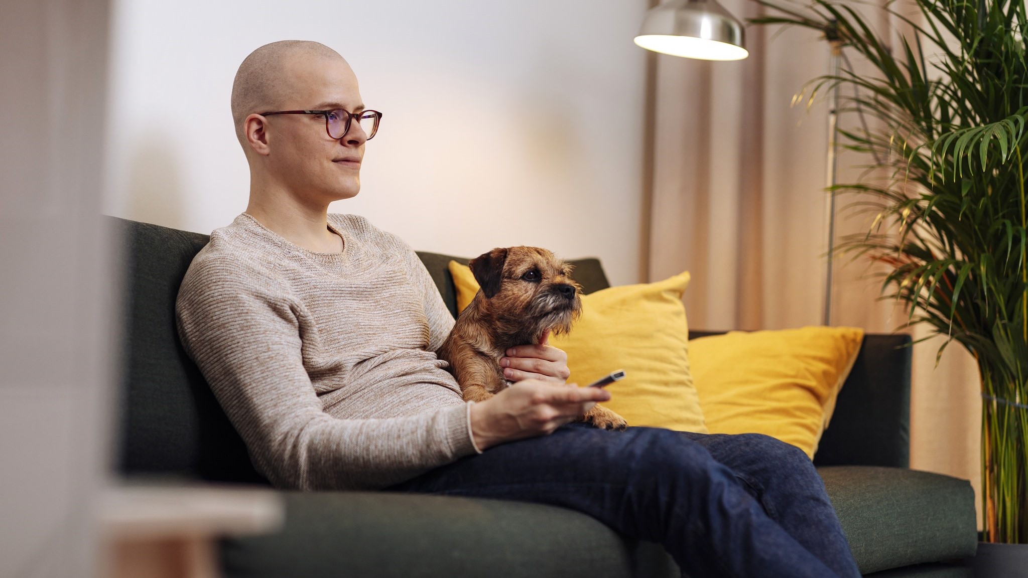 A man watches television on the couch with a dog. (Image: Mika Pakarinen, Keksi / LVM)