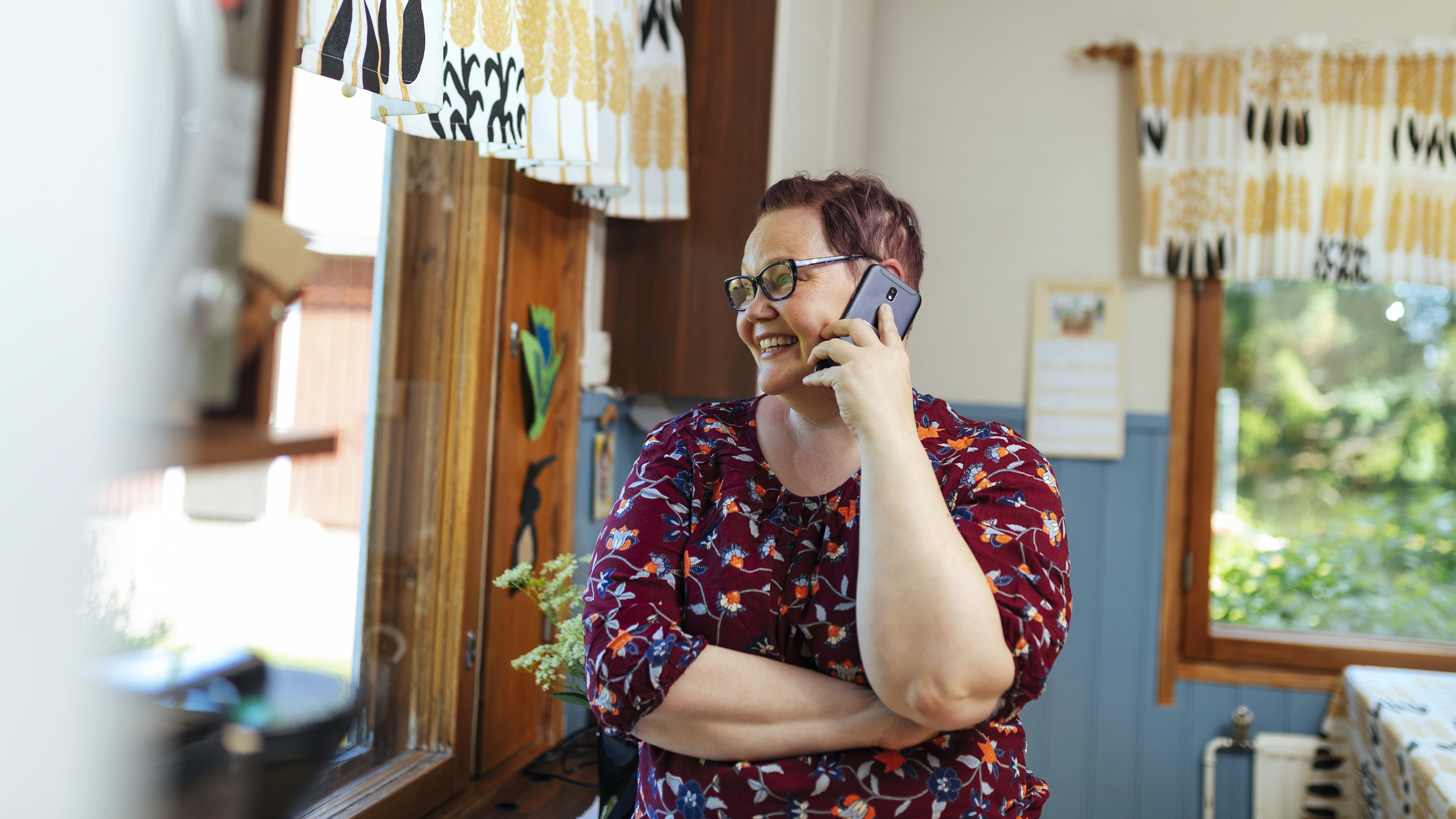 Nainen puhuu puhelimessa kotona ikkunan ääressä. (Kuva: Mika Pakarinen, Keksi)