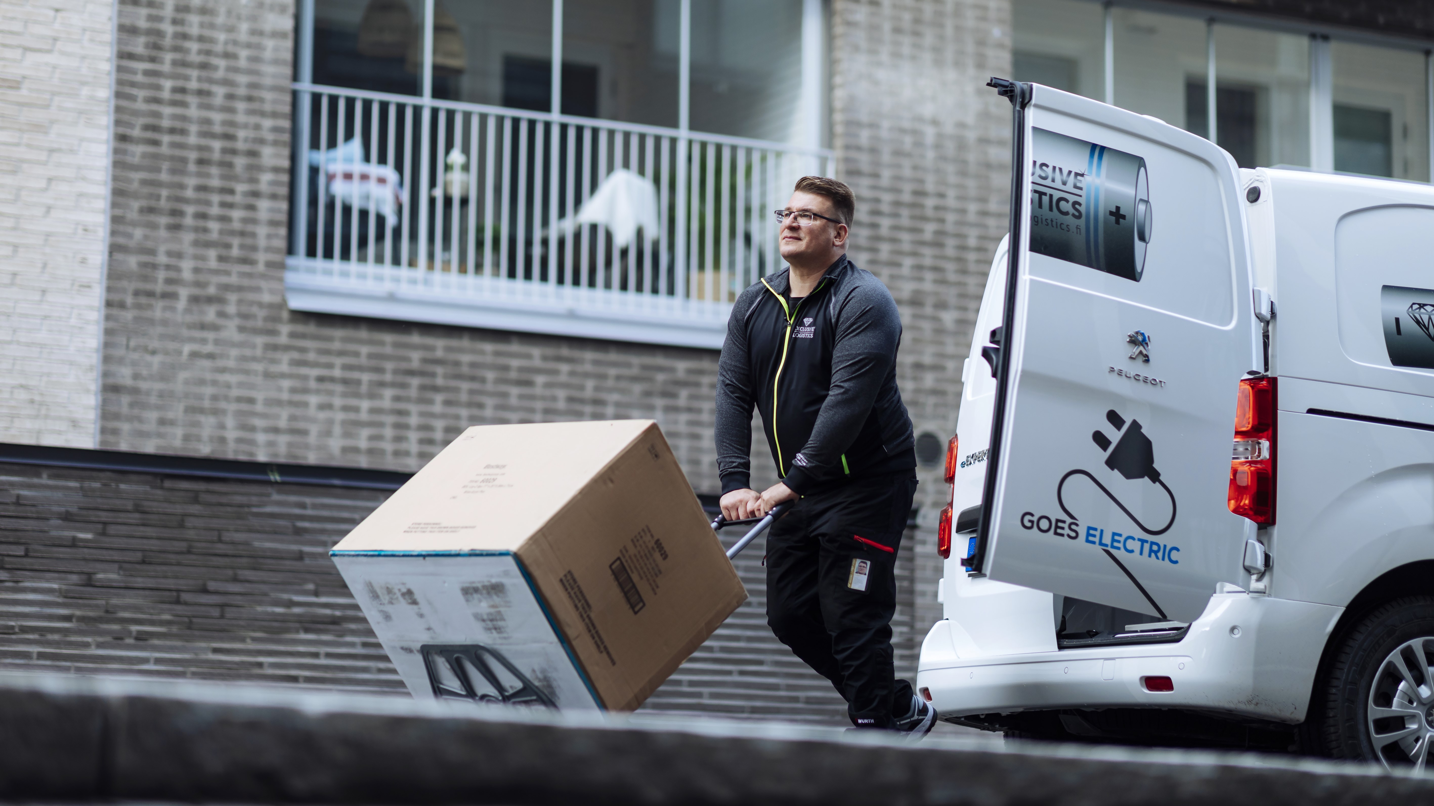 A man moves a package on a cart from a delivery van (Kuva: Mika Pakarinen / Keksi Agency)