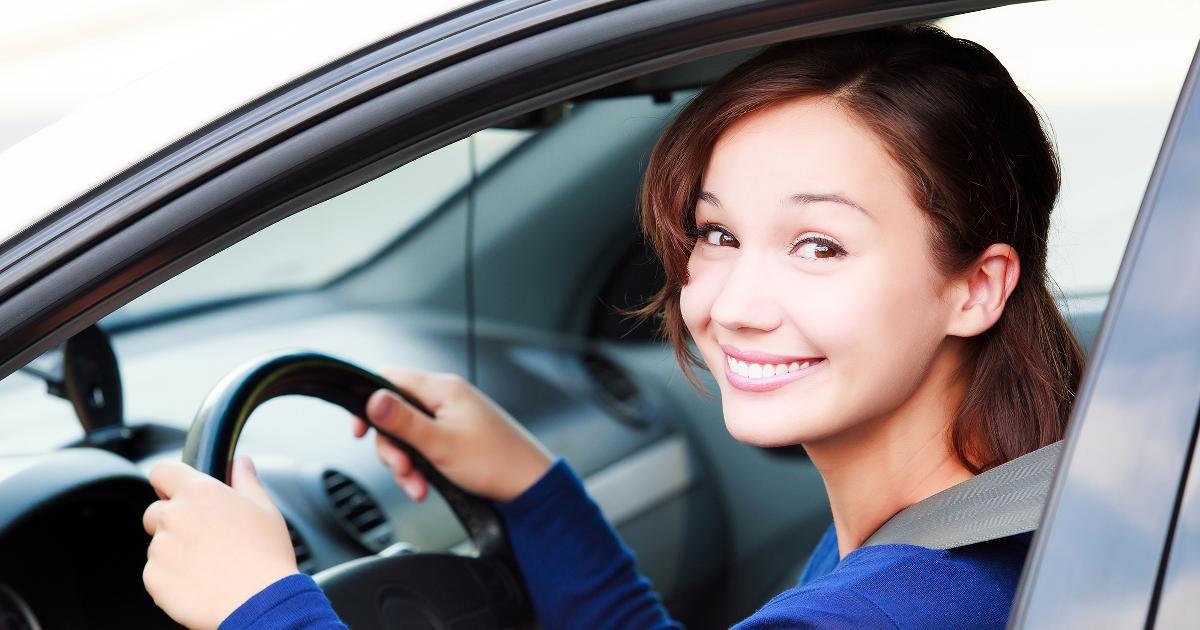 Autoileva nuori nainen katsoo ikkunasta, kädet ratissa ja turvavyö kiinni (Kuva: Shutterstock)