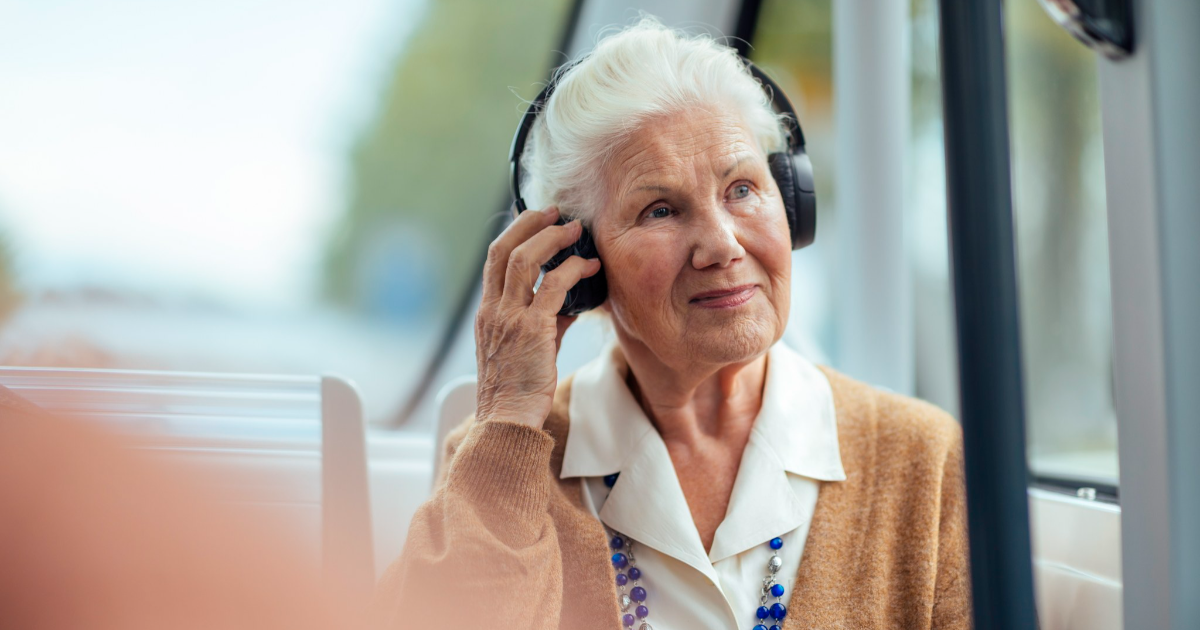 Nainen kuulokkeet päässä bussissa (Kuva: Mika Pakarinen / Keksi, LVM)
