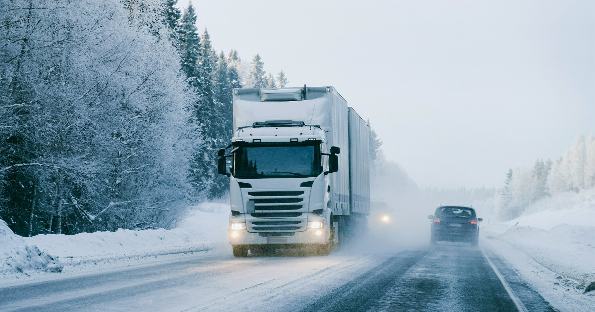 A truck and a car on a snowy highway. (Image: Shutterstock)