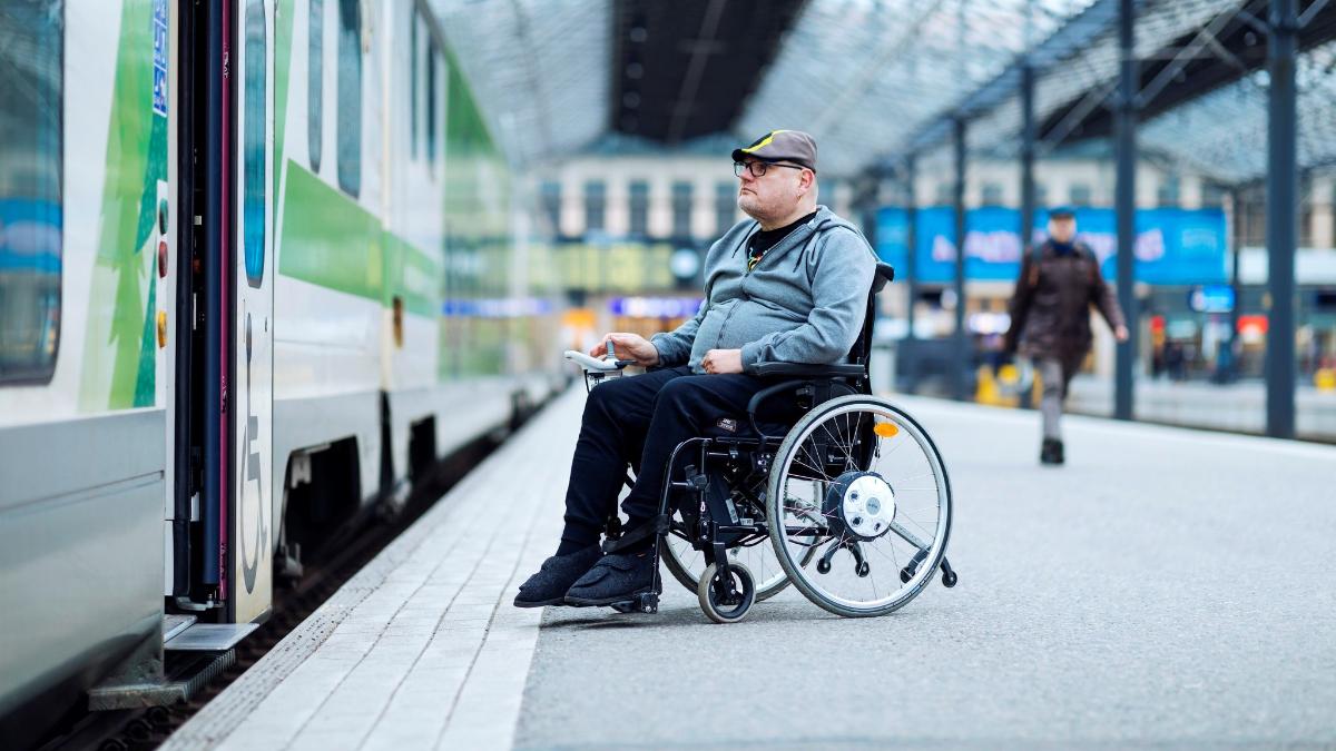 Mies nousemassa junaan pyörätuolissa rautatieasemalla.