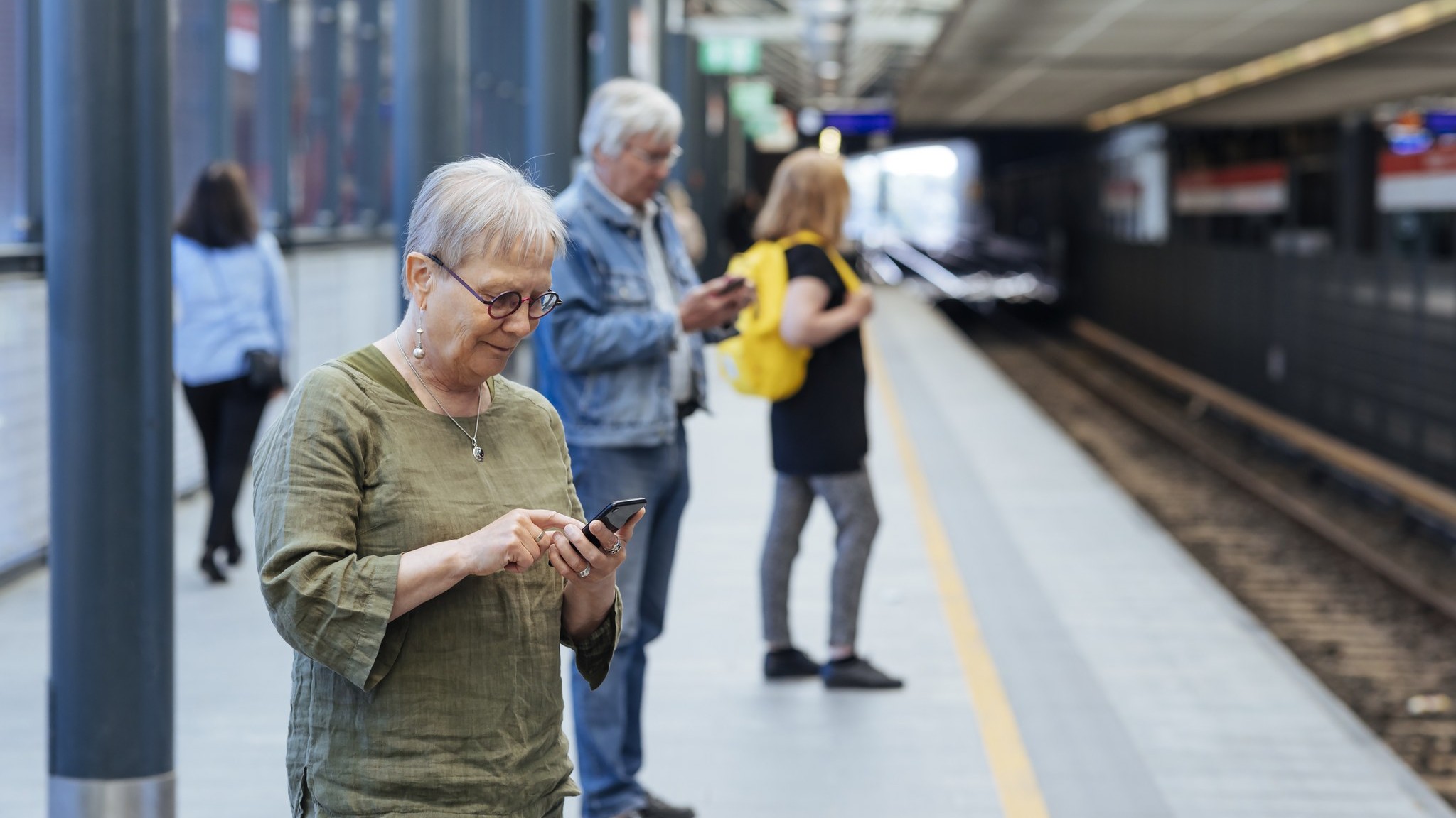 Nainen käyttää puhelinta metroasemalla (Kuva: Mika Pakarinen Keksi/LVM)