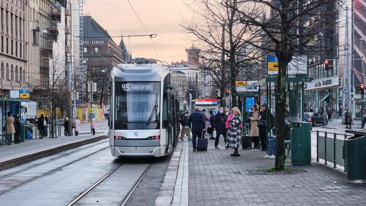 Ihmisiä ja raitiovaunu pysäkillä talvisessa Helsingissä.