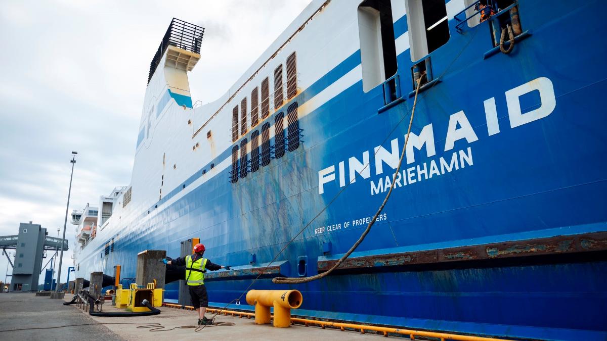Finnmaid-niminen alus satamassa. Etualalla satamatyöntekijä kiinnittää köysiä.