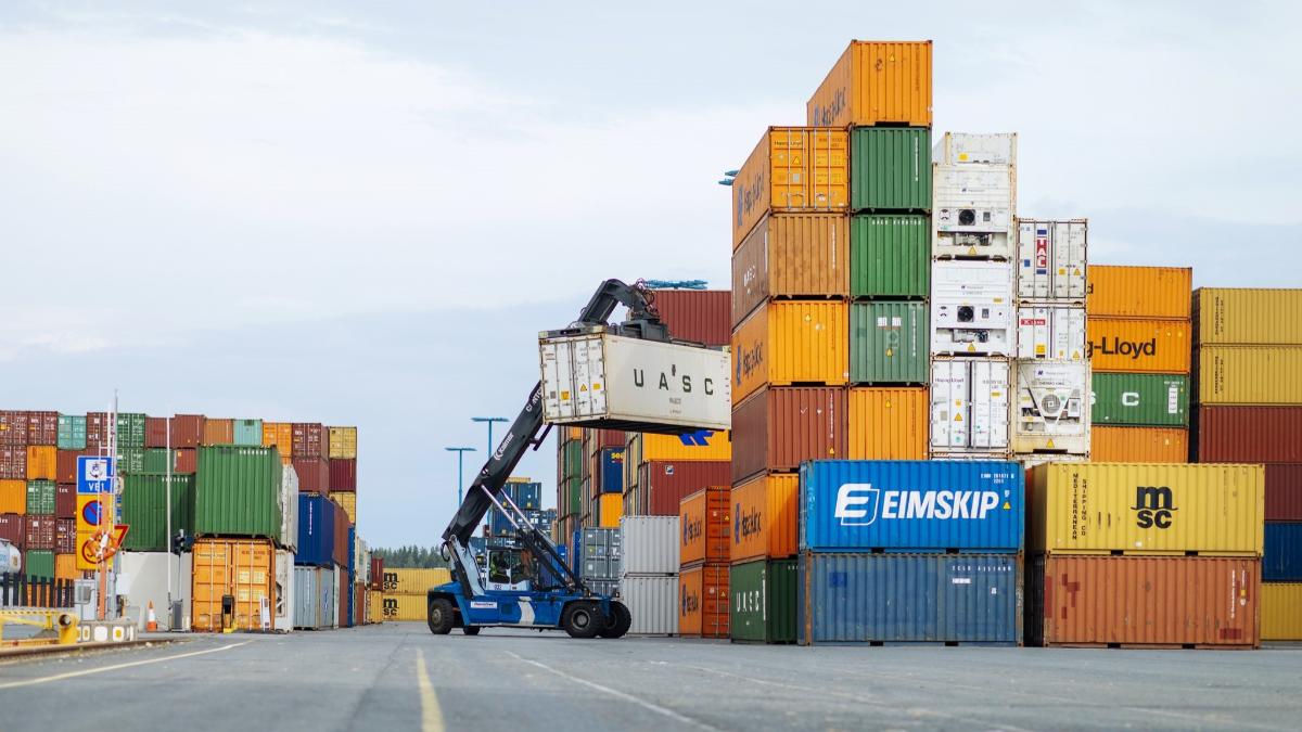 Työkone siirtää kontteja satamassa.