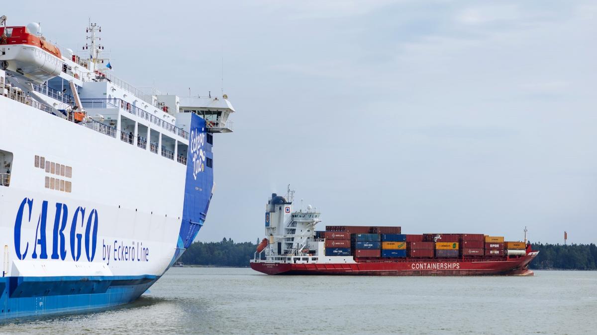 Kaksi rahtialusta merellä lähellä rantaa, taustalla näkyy havumetsää.