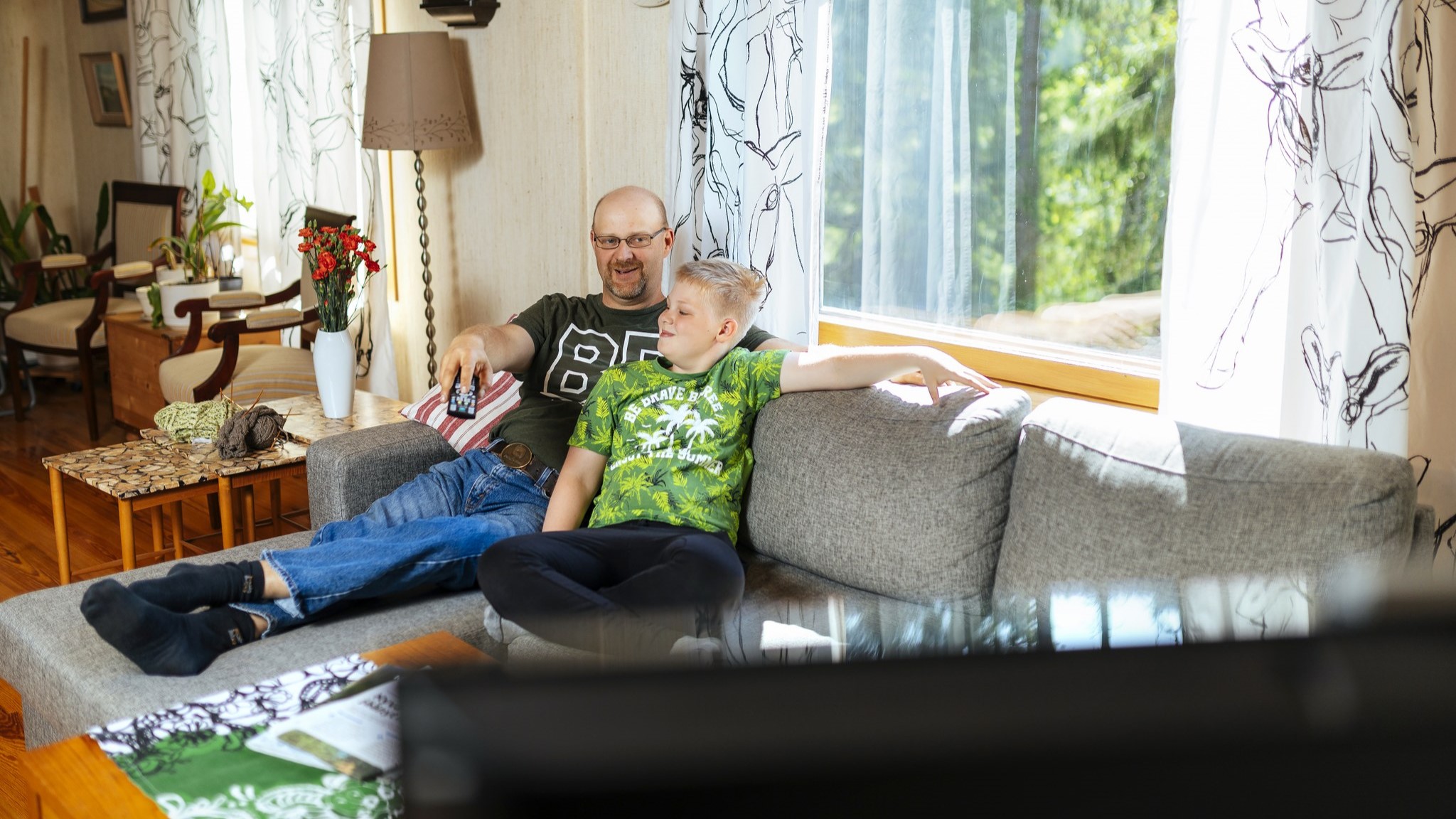 Ett barn och en förälder tittar på TV. (Bild: Mika Pakarinen, Keksi / LVM)
