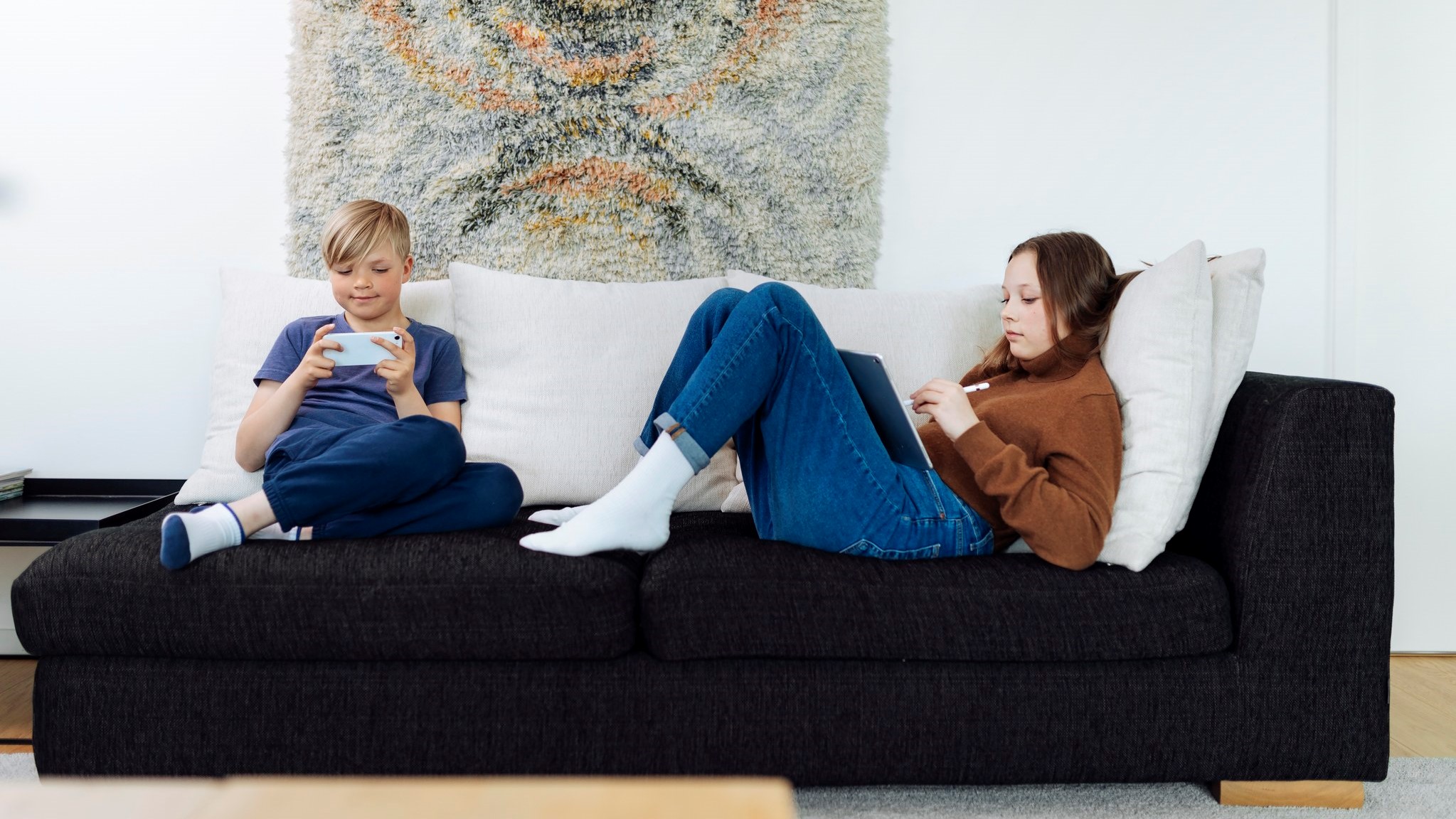 Lapset sohvalla käyttämässä älylaitteita. (Kuva: Mika Pakarinen, Keksi/LVM)